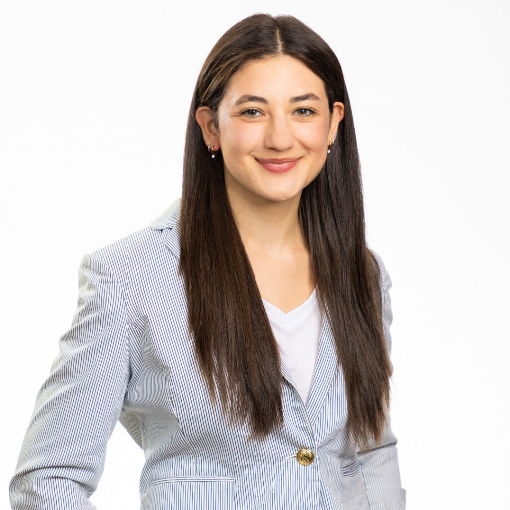 Rachel Gott smiles at the camera wearing a blue and white striped blazer against a white background. Rachel works in Creator Success at Globe Thrivers supporting creators on the travel planning platform.
